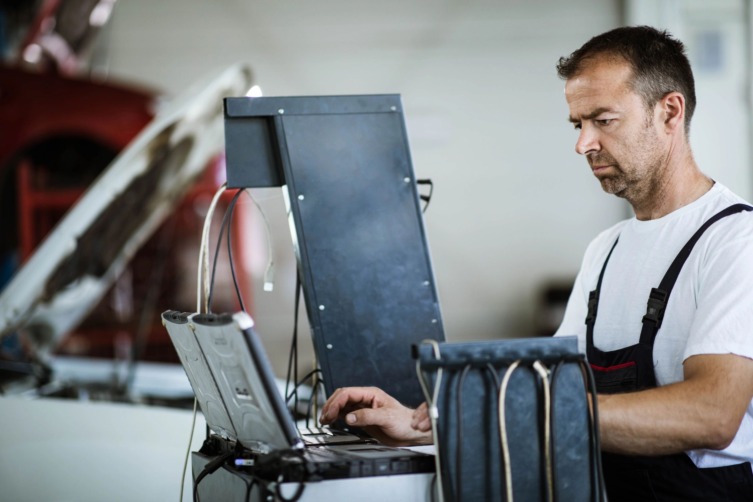 Mechanic using a laptop for vehicle diagnostics in a repair shop